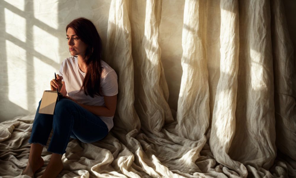 Person sitting alone, thinking about emotional pain, which is a symbol of the 4 main causes of depression.